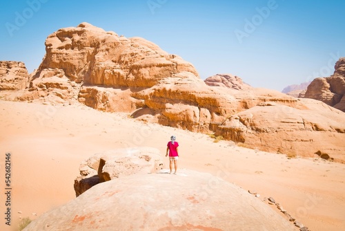 Girl tourist stand on famous arch bridge in wadi rum desert pose and enjoy panoramic view of scenic rock formations