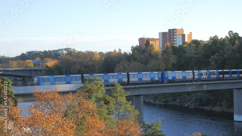 Stockholm, Sweden - 10.29.2022: Subway train passing by on a bridge from Bergshamra to Danderyds sjukhus. 4K high vantage point view on a clear autumn day at sunset. photo