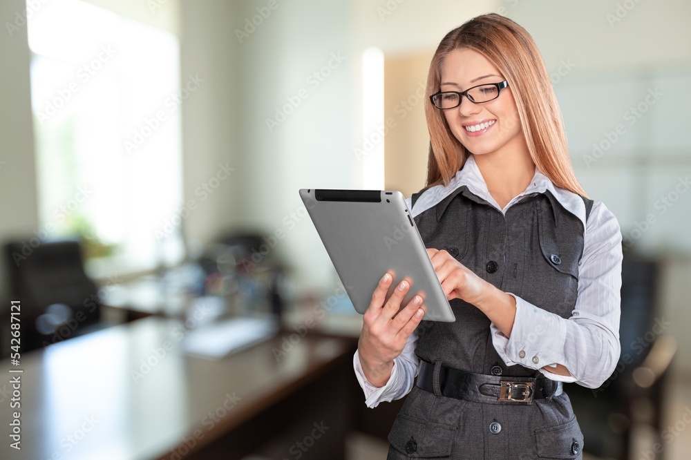 Young business woman working on digital tablet on office background Young business woman working on digital tablet on office background