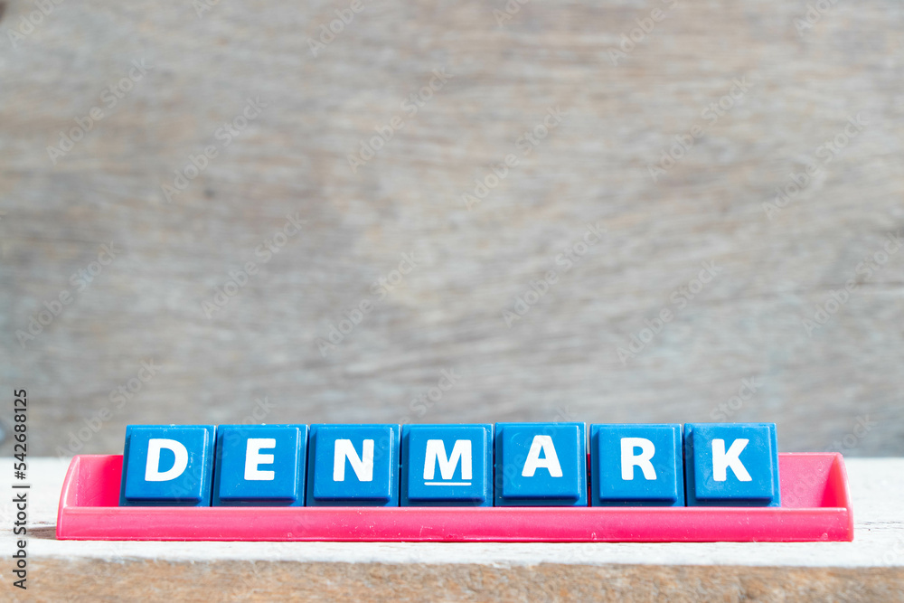 Tile alphabet letter with word denmark in red color rack on wood background