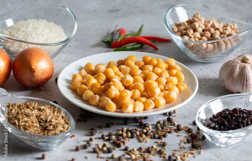 Boiled chickpeas and ingredients for vegetarian pilaf on a light background