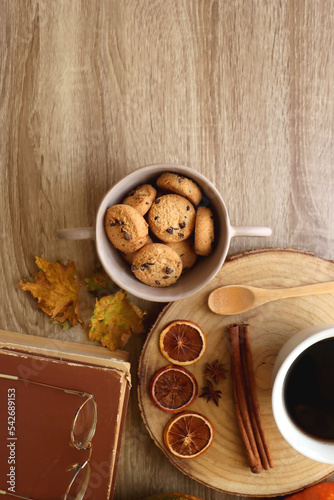 Cup of tea or coffee, seasonal spices, bowl of cookies, blanket, pumpkins, colorful leaves, books and tangerines on wooden table. Cozy hygge at home. Top view. © jelena990