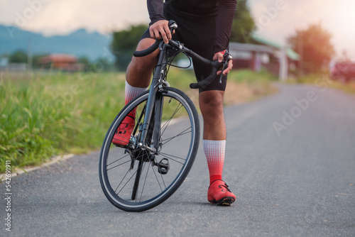 Asian man taking break resting from tiredness exhaustion, cycling on bike in the morning on a road adventure nature, wearing cycling clothing, exercising healthy lifestyle activity leisure sport © Have a nice day 