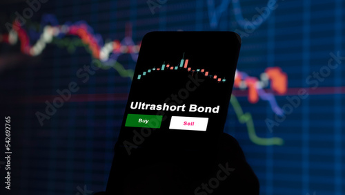 An investor's analyzing the Ultrashort Bond etf fund on screen. A phone shows the ETF's prices ultrashort bond to invest photo