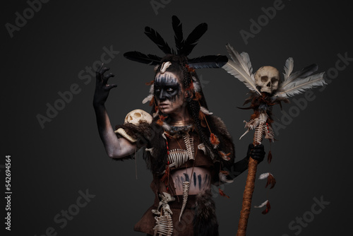 Studio shot of dark voodoo witch with painted face holding staff. © Fxquadro