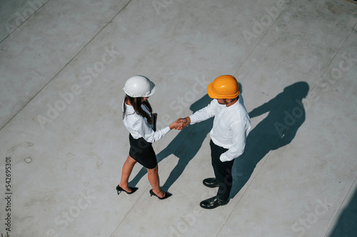 Successful deal, doing handshake. Man with woman are working on the construction project together outside