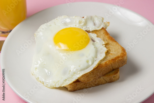 Fried eggs on a pink background. Breakfast of Fried eggs on fried bread and a glass of juice
