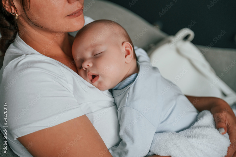 Close up view of cute baby that sleeping on the mother's chest Close up view of cute baby that sleeping on the mother's chest