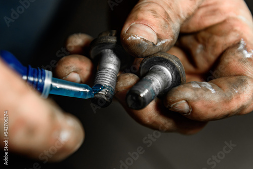 A man lubricates wheel bolts with grease.