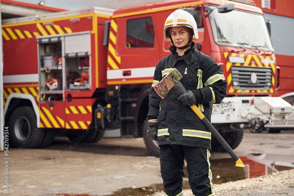 In uniform with axe in hands. Woman firefighter is at work in department In uniform with axe in hands. Woman firefighter is at work in department