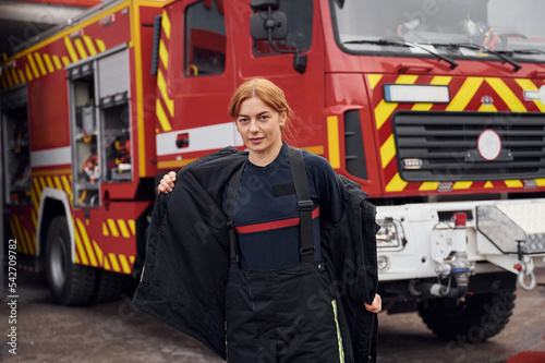 Taking off the protective clothes. Woman firefighter in uniform is at work in department photo