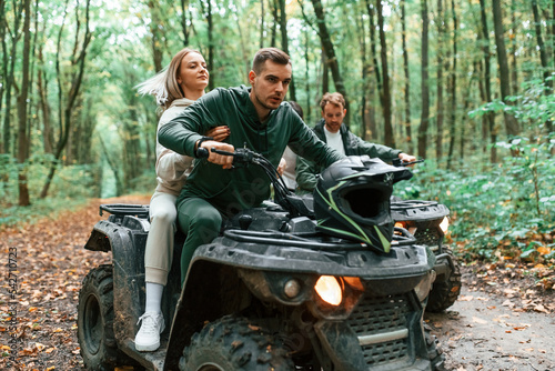 Riding and smiling. Young couple riding a quad bike in the forest