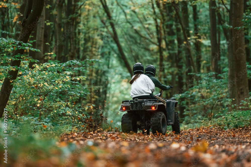 Driving on the footpath. Young couple riding a quad bike in the forest Driving on the footpath. Young couple riding a quad bike in the forest