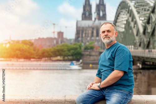 Stampa su tela bearded man sitting on embankment of Rhine on background of Cologne Cathedral and Hohenzollern Bridge in Koel, Germany