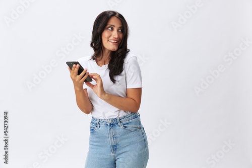 Woman blogger with a phone in her hands photo content, video call, selfie smile with teeth in a white t-shirt on a white background, copy space, emotions and gestures signals