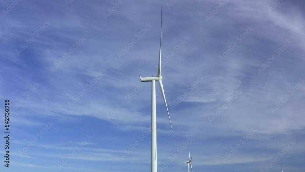 Wind turbines towers on electricity farm spinning and producing green energy Wind turbines towers on electricity farm spinning and producing green energy