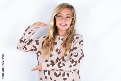 little caucasian kid girl wearing animal print sweater over white background gesturing with hands showing big and large size sign, measure symbol.