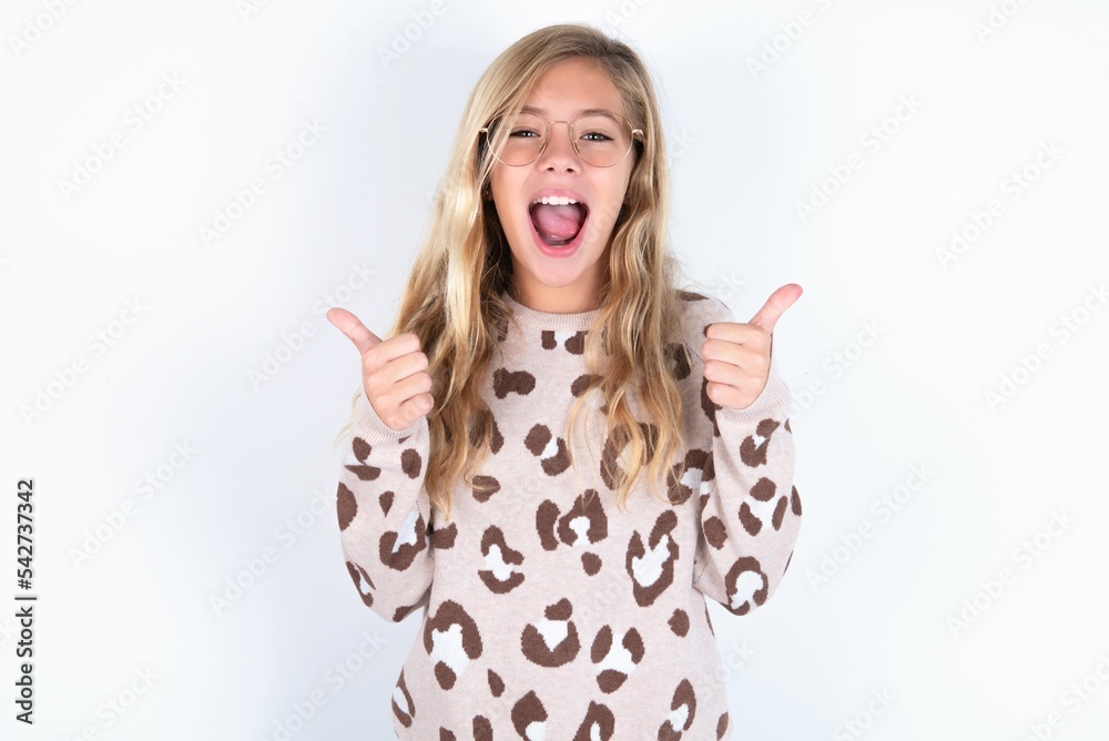 Φωτογραφία Optimistic beautiful caucasian teen girl wearing animal print sweater over white wall showing thumbs up with positive emotions