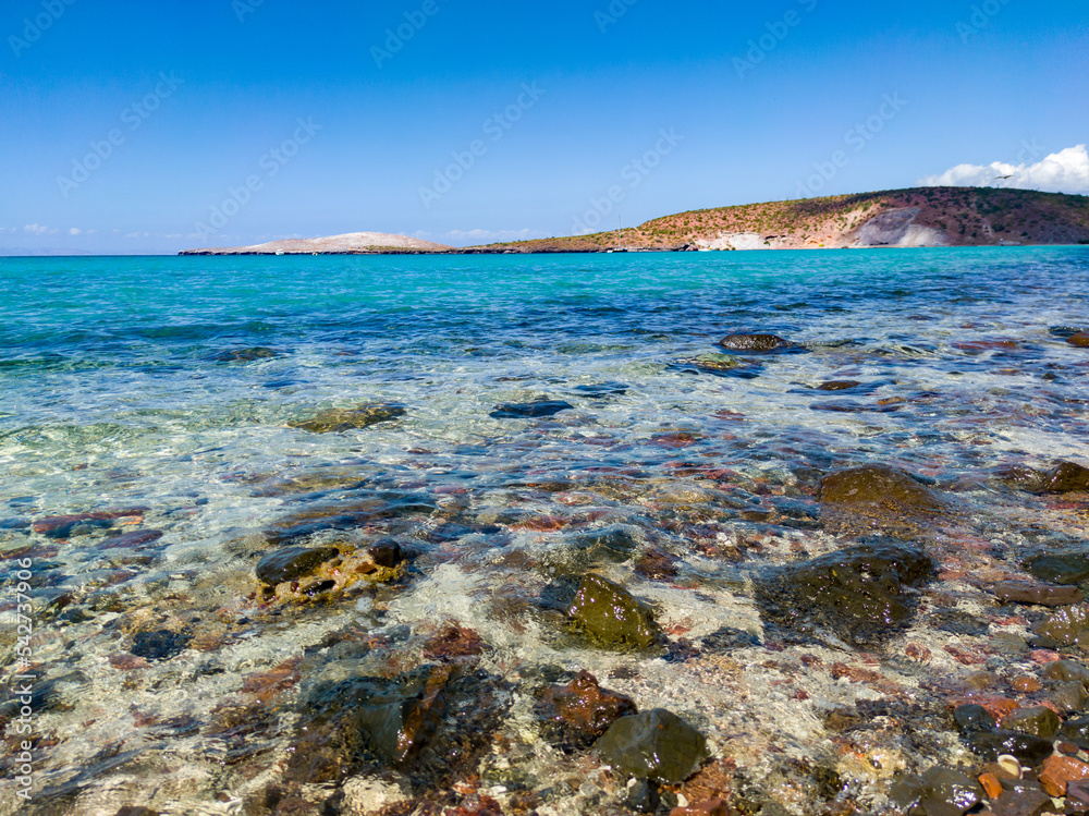 View of the edge of the pacific ocean beach with small rocks in the water. idyllic landscape