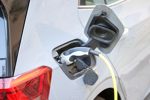 Ein Elektro Auto wird an einer Ladestation mit Hilfe eines Ladekabels aufgeladen.