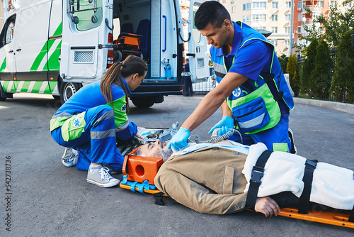 Fototapeta Ambulance paramedic with defibrillator performing cardiopulmonary resuscitation