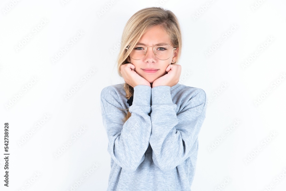 Portrait of sad beautiful caucasian teen girl wearing gray sweater over white wall hands face Portrait of sad beautiful caucasian teen girl wearing gray sweater over white wall hands face
