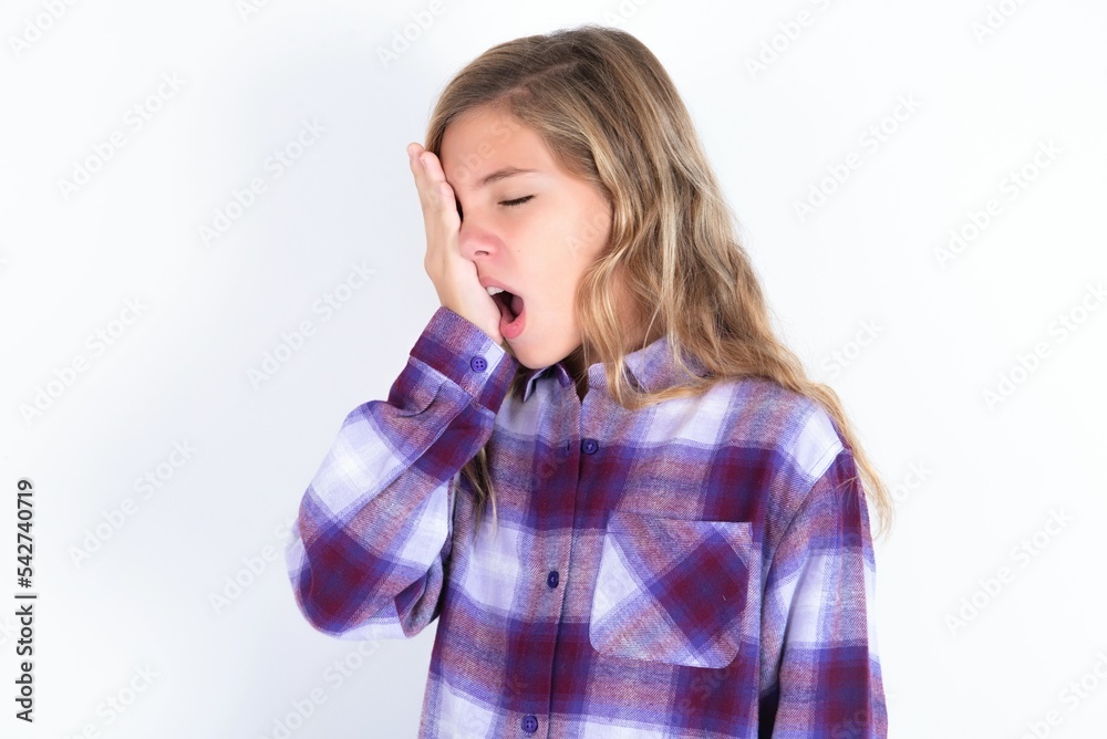 beautiful caucasian teen girl wearing plaid purple shirt over white wall Yawning tired covering half face, eye and mouth with hand. Face hurts in pain. beautiful caucasian teen girl wearing plaid purple shirt over white wall Yawning tired covering half face, eye and mouth with hand. Face hurts in pain.