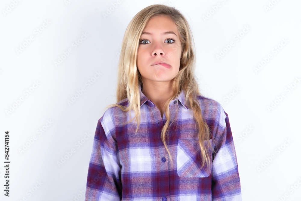 beautiful caucasian teen girl wearing plaid purple shirt over white wall making grimace and crazy face, screaming out of control, funny lunatic expressing freedom and wild. beautiful caucasian teen girl wearing plaid purple shirt over white wall making grimace and crazy face, screaming out of control, funny lunatic expressing freedom and wild.