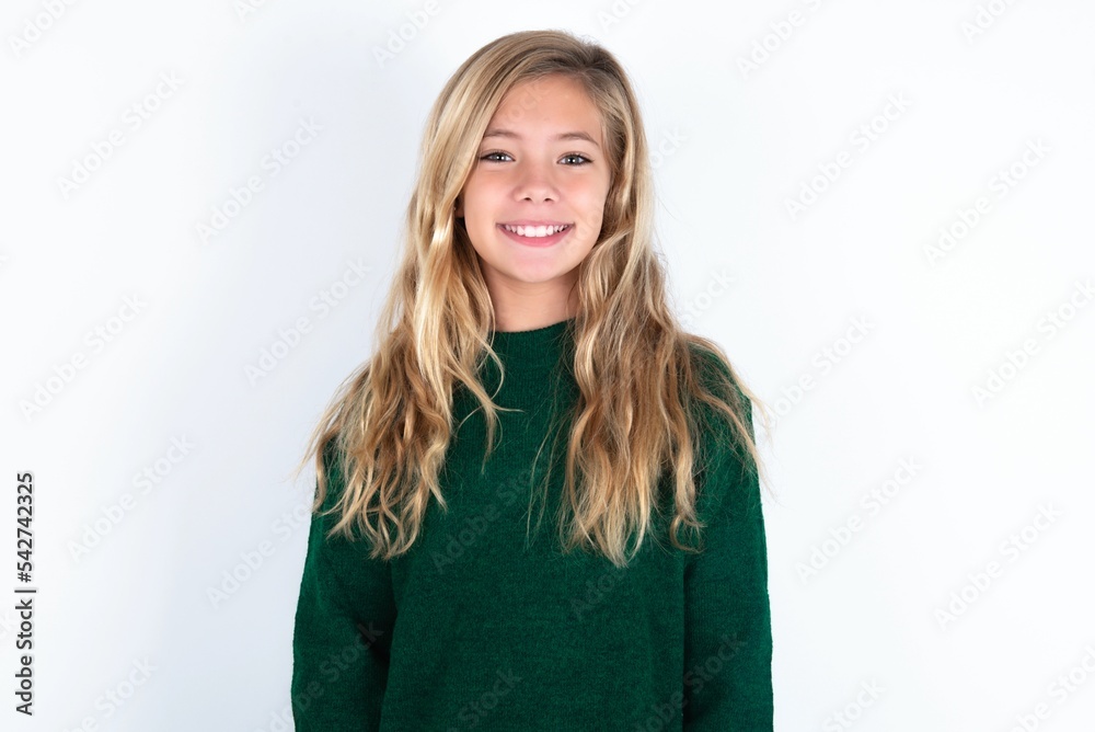 beautiful caucasian teen girl wearing green knitted sweater over white wall with nice beaming smile pleased expression. Positive emotions concept beautiful caucasian teen girl wearing green knitted sweater over white wall with nice beaming smile pleased expression. Positive emotions concept