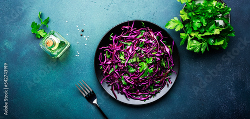 Healthy food salad with red cabbage, carrot, parsley and olive oil dressing on white kitchen table background, top view photo