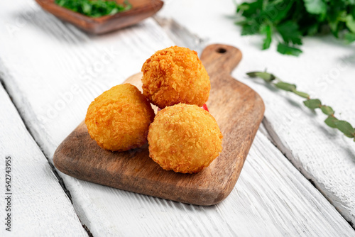 Fried potato croquettes with cheese on a wooden board. Snack with potato balls photo