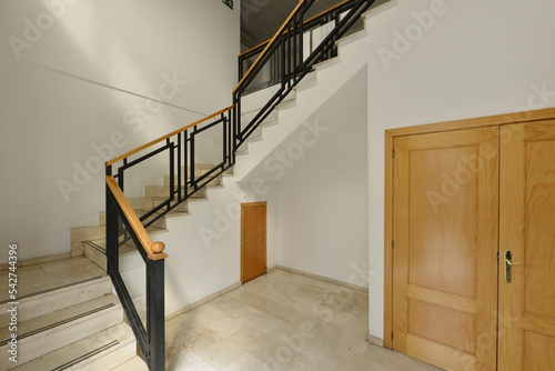 Stairs with marble steps and wooden and black painted metal handrails