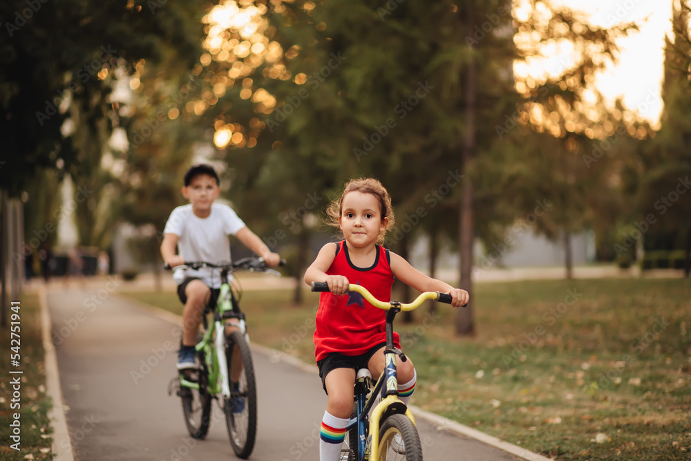 Two little boy and girl cyclists riding their bikes and enjoy having fun. Kid outdoors sport summer activity. Two little boy and girl cyclists riding their bikes and enjoy having fun. Kid outdoors sport summer activity.
