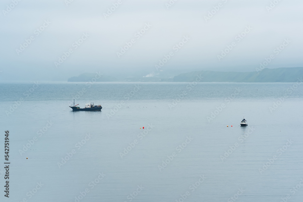 fishing boats at sea against the background of a distant foggy coast fishing boats at sea against the background of a distant foggy coast