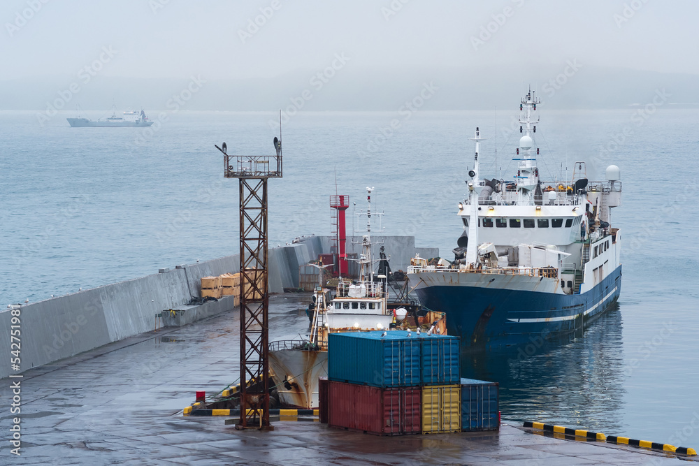 Naklejka premium fishing boat at the pier in the harbor on the shore of a cloudy sea