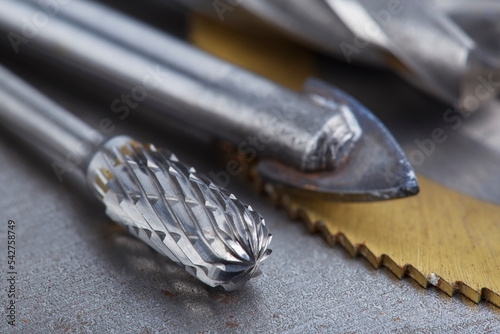 set of different drill bits,thread tap and mill cutters with caliper ruler on steel plate background. Locksmithing deal.