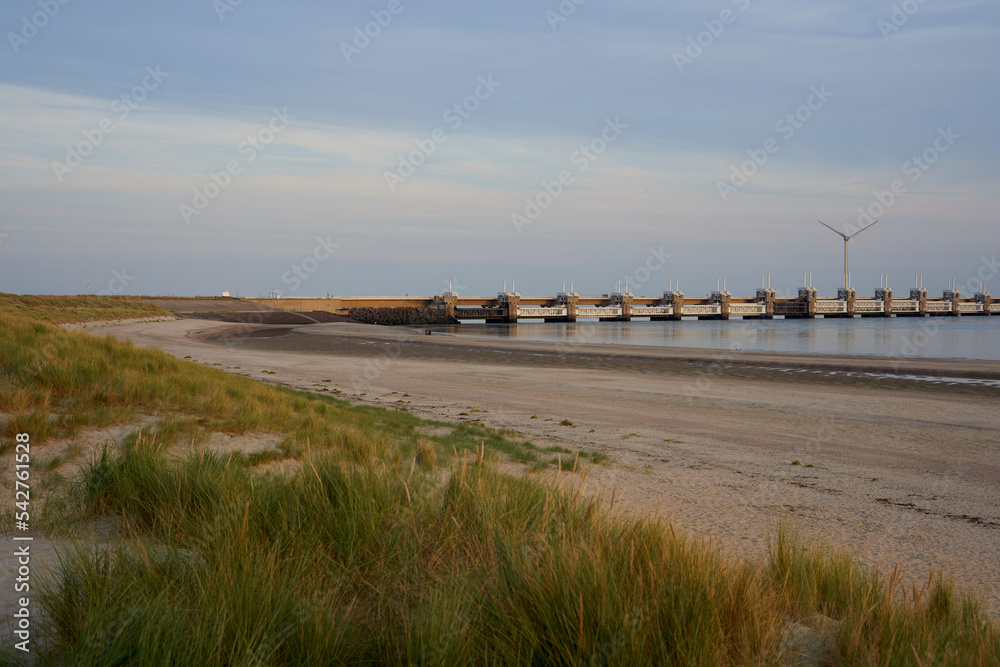 Dutch storm surge barrier (Deltawerke) on the water. Bridge with buildings for protection against high water also flood. In the evening before the beach. Netherlands, Zeeland.