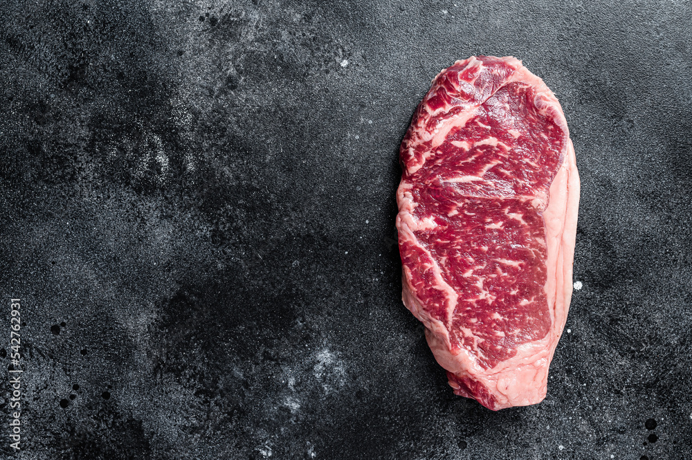 Raw Striploin steak, beef butchery cut. Black background. Top view. Copy space