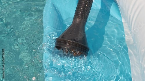 Close-up clean water is poured into an inflatable pool from a hose. Sunny day
