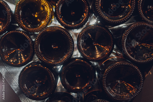 Close-up shot, old bottles of wine in a cellar. Glass wine cabinets covered with dust due to long storage. Warm, muted tones. Bottles textere. photo
