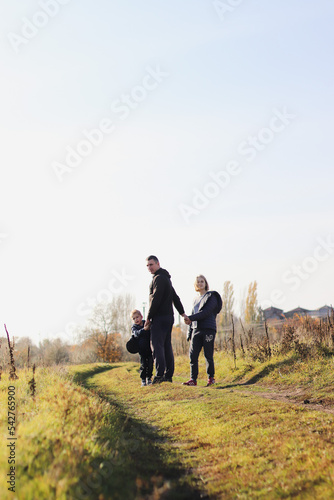 a path trodden along a wild field in autumn and a silhouette of a father with children in front selective focus