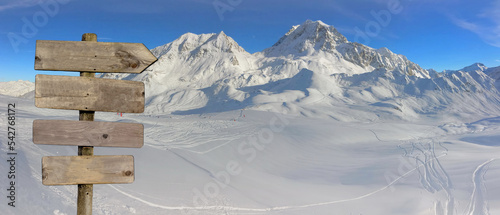 wooden directional post with arrow pointing right on  ski slopes in snow capp...