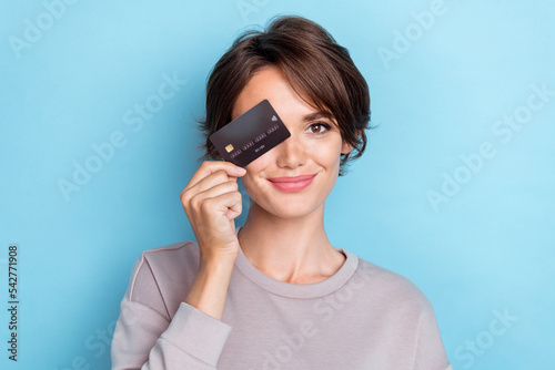 Portrait of positive cheerful gorgeous girl bob hairdo wear gray sweatshirt plastic card cover eye isolated on blue color background