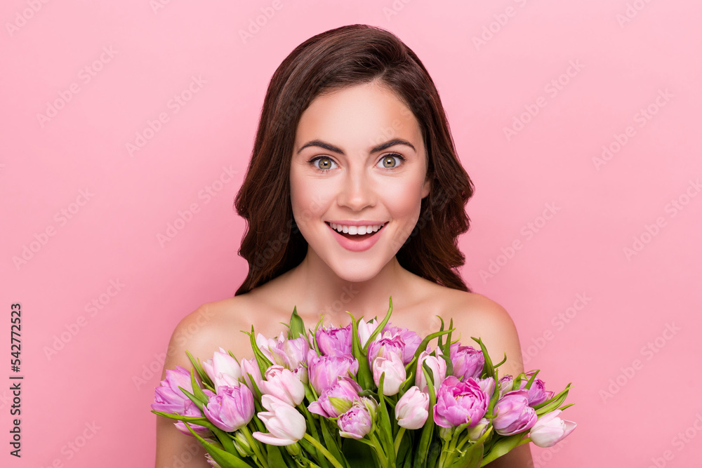 Photo of impressed funny young nude lady wear nothing holding tulips bloom isolated pink color background