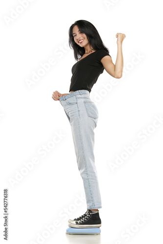 Weight loss happy woman standing on a scale, isolated on a white background. Slim Body