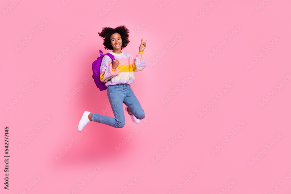 Full length photo of pretty shiny small kid wear striped sweater jumping high showing v-sign empty space isolated pink color background