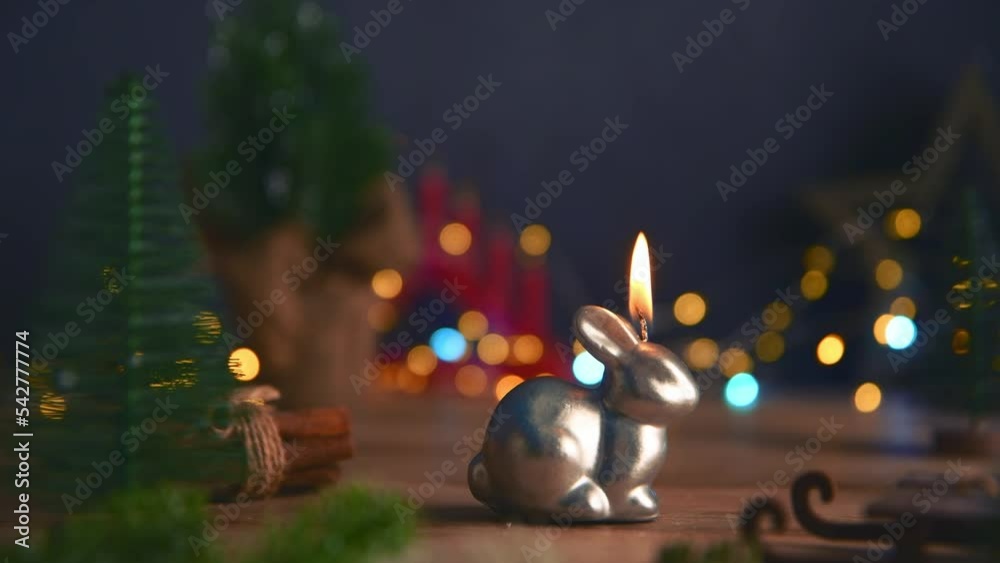 candle in the form of a rabbit symbol of 2023 among the lights, garlands, Christmas trees, chinese calendar year symbol