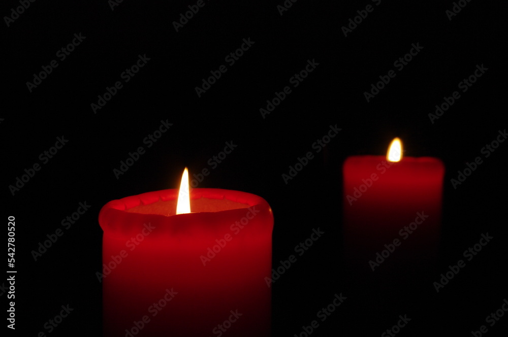 Two red candles on a dark background, emphasizing the flame Two red candles on a dark background, emphasizing the flame