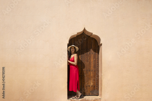 Sexy tourist woman on an Arab wall of the fortress of the Menara Gardens in Marrakech enjoying the construction of the ancient Almoravids and their parks, is one of the most visited places in Morocco. photo