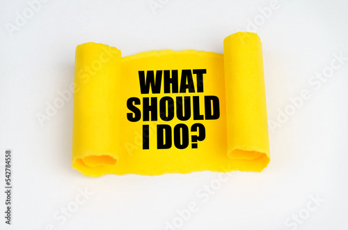 On a white surface, a yellow scroll of paper with the inscription - WHAT SHOULD I DO